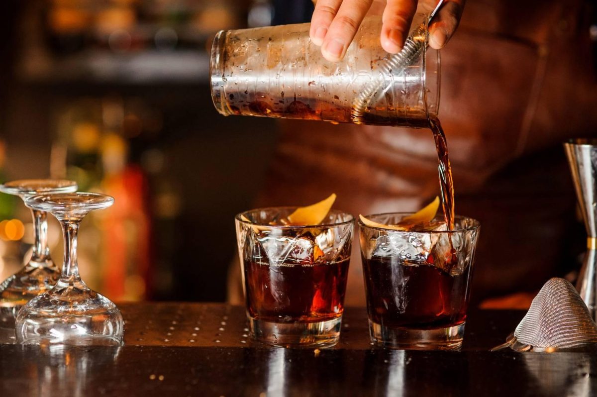 Serveur préparant des cocktails alcoolisés dans un bar-restaurant avec ambiance tamisée, illustrant les règles françaises encadrant la vente d’alcool, les happy hours et les restrictions imposées aux établissements.