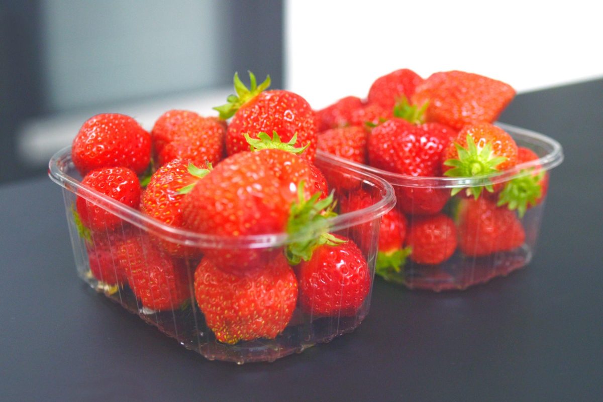Barquettes de fraises rouges fraîches posées sur une surface sombre, illustrant les fruits vendus en supermarché et les interrogations sur la présence de résidus de pesticides et contaminants alimentaires
