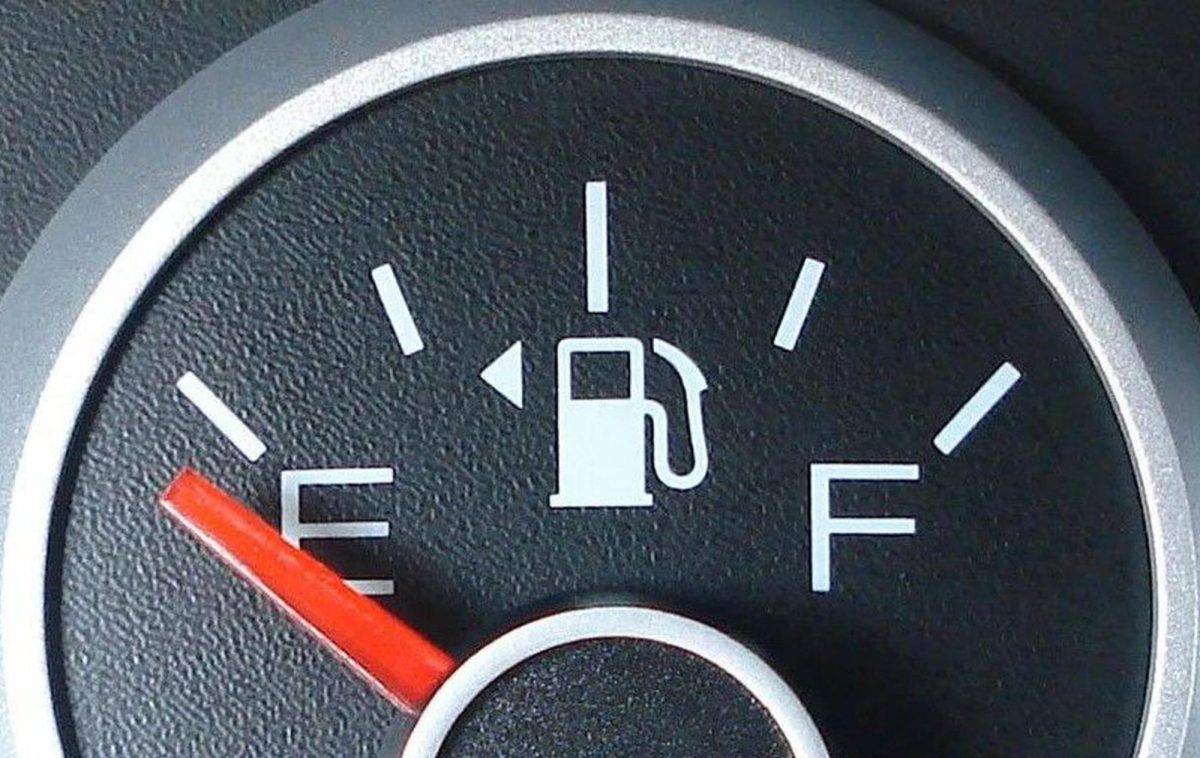 Jauge de carburant d’une voiture affichant presque la réserve avec l’aiguille rouge proche du niveau vide sur le tableau de bord d’un véhicule.