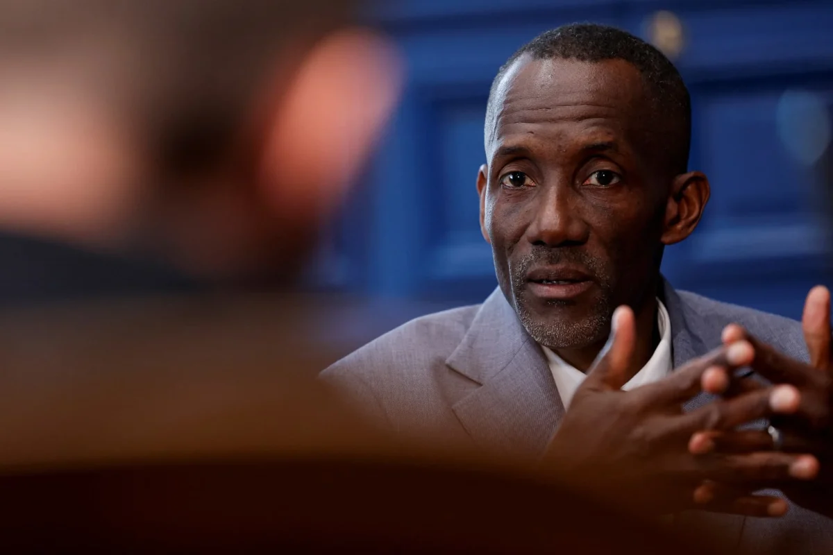 Portrait d’un maire français en pleine interview politique dans un bureau municipal, expression sérieuse et gestes des mains visibles, illustration des tensions autour du décrochage du portrait présidentiel dans une mairie de Seine-Saint-Denis.