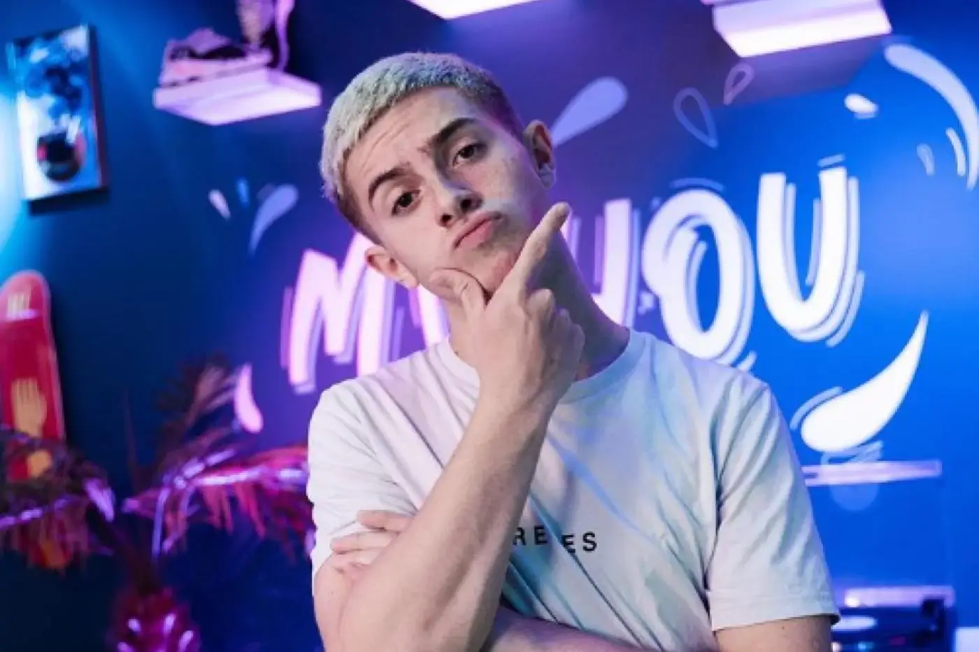 le youtubeur Michou pose dans un décor lumineux aux couleurs bleues et violettes avec une expression interrogative, illustration utilisée dans un article sur la polémique entourant son fast-food à Paris
