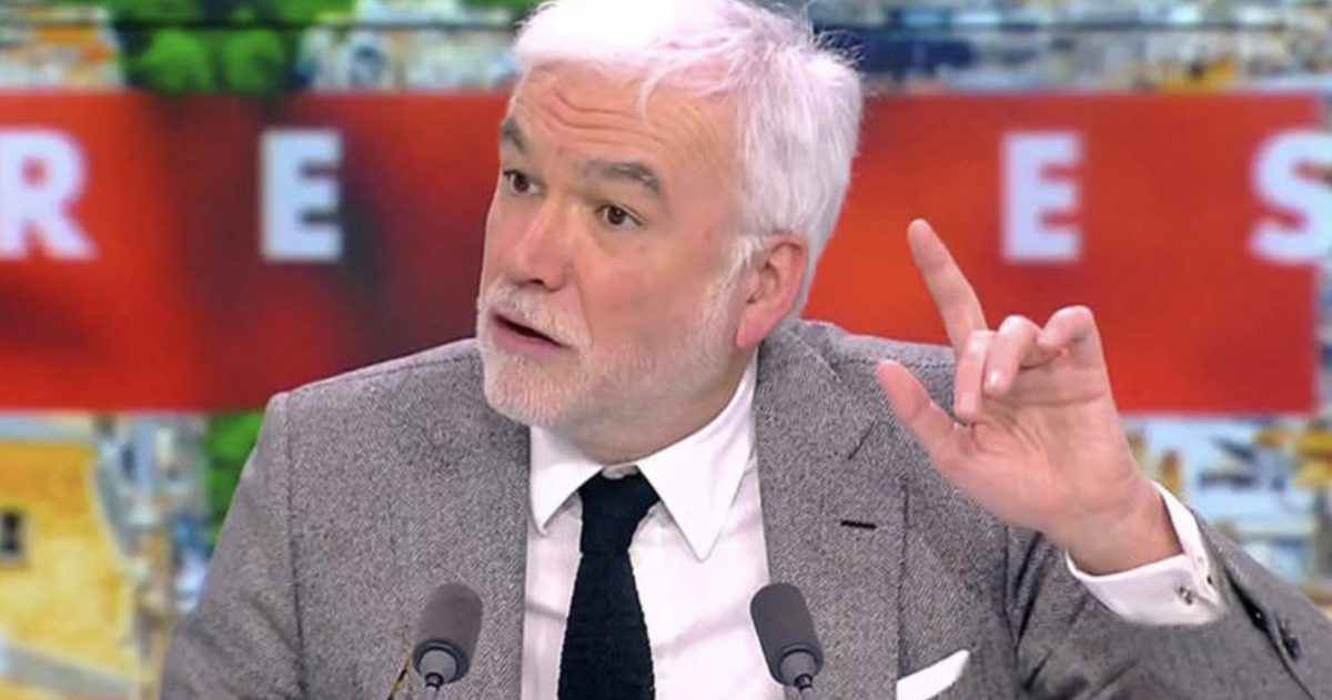 animateur de télévision en plein débat sur un plateau d’information levant la main face aux caméras dans une ambiance tendue de direct télévisé