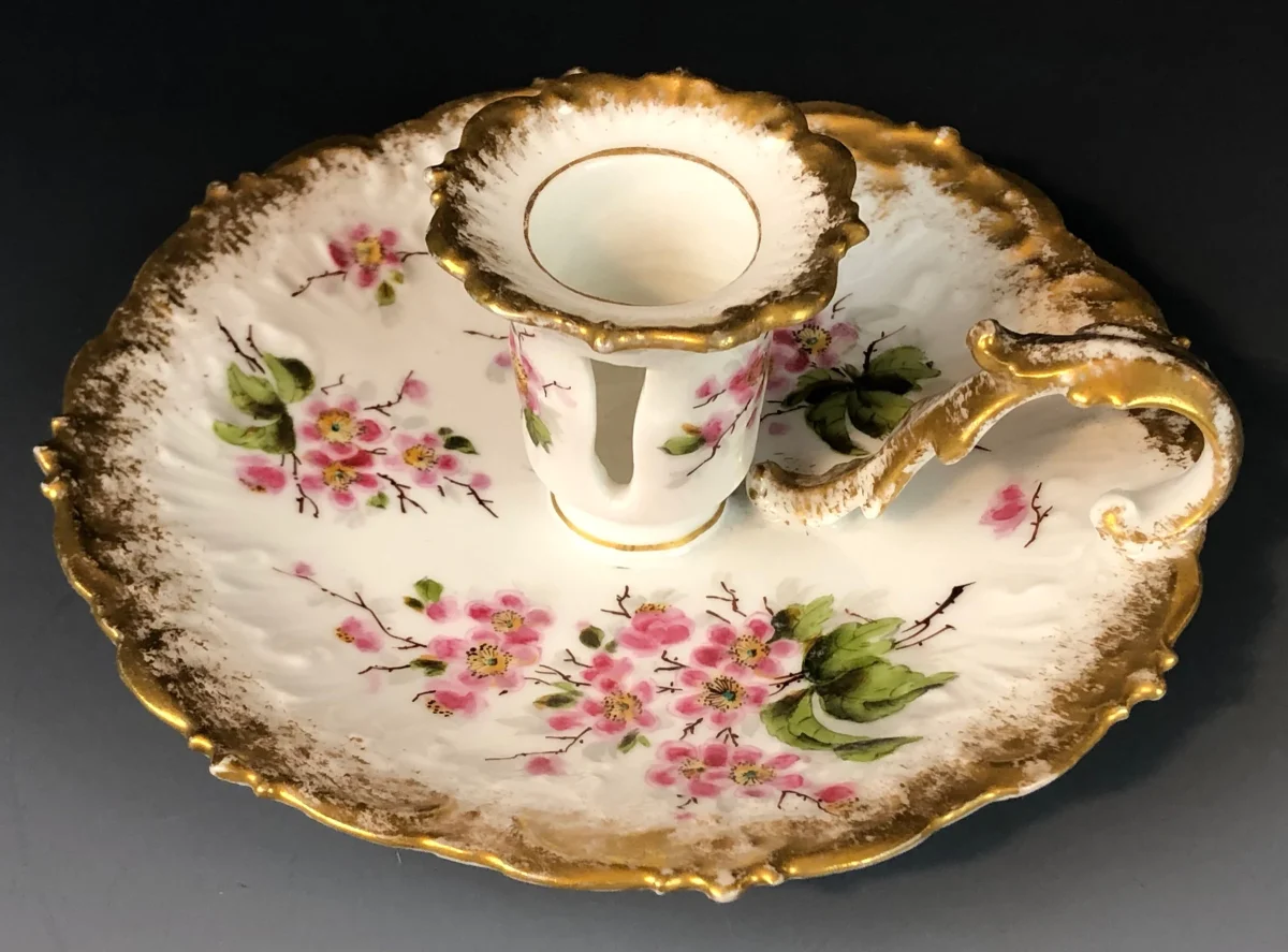Bougeoir ancien en Porcelaine de Limoges décoré de motifs floraux roses peints à la main avec finitions dorées raffinées, présenté sur fond sombre dans un style élégant et vintage.