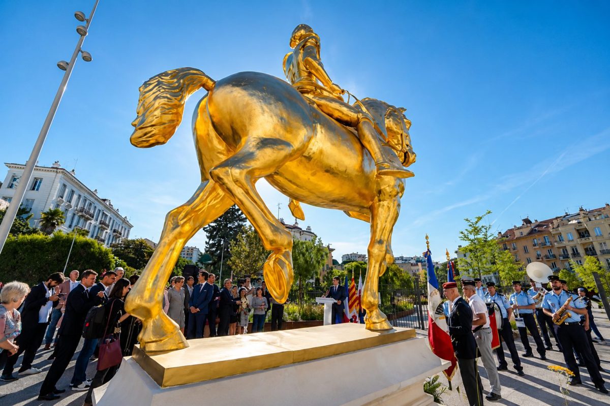 Grande statue dorée de Jeanne d’Arc à cheval installée à Nice lors d’une cérémonie officielle en présence d’élus, de policiers municipaux et d’habitants, sous un ciel bleu lumineux dans le quartier de la Libération.