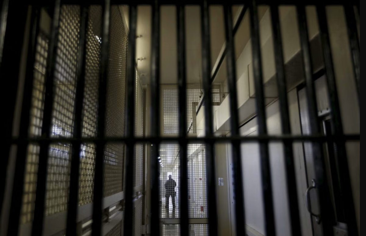 Vue d'un couloir de prison française photographié derrière des barreaux métalliques, illustrant les conditions de détention et le débat sur la climatisation des établissements pénitentiaires pendant les épisodes de canicule en France.