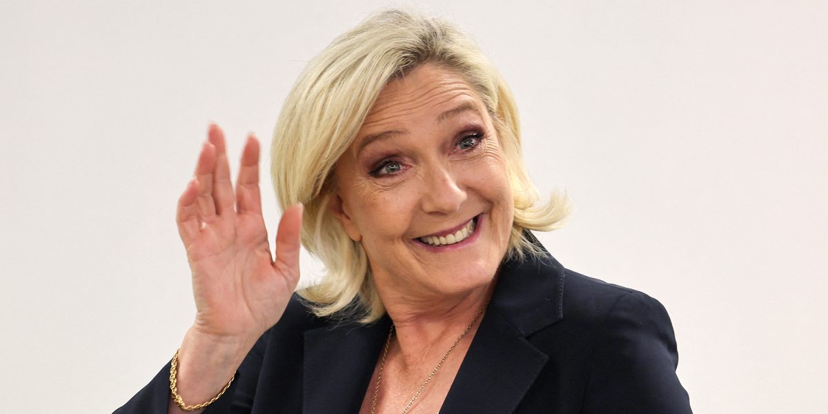 Marine Le Pen, présidente du Rassemblement national (RN), sourit et salue de la main lors d'un événement public. Vêtue d'une veste noire, elle apparaît en gros plan sur un fond clair. Cette photographie illustre un article consacré à sa vie privée, à son célibat, à sa colocation avec sa meilleure amie Ingrid, aux rumeurs ayant circulé sur leur relation et aux déclarations par lesquelles elle avait affirmé être heureuse de vivre seule et de ne pas vouloir d'une nouvelle relation amoureuse.