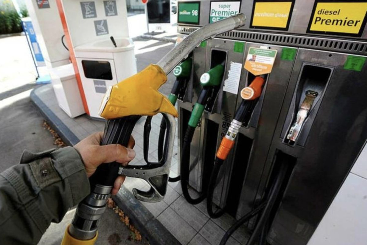 Pompe à carburant tenue par un automobiliste dans une station-service moderne, avec plusieurs pistolets d’essence et de diesel visibles en arrière-plan. Cette scène illustre le ravitaillement d’un véhicule dans un contexte marqué par les préoccupations liées au prix du carburant, aux vols à la pompe et aux départs sans paiement.