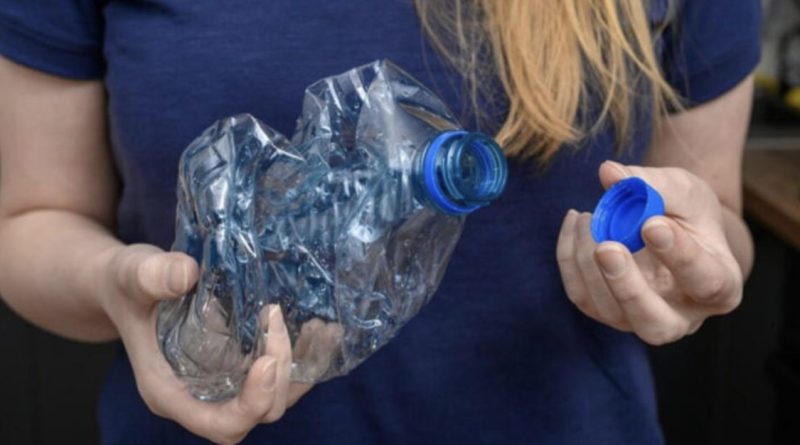 Personne tenant une bouteille en plastique PET écrasée avec son bouchon à la main, illustrant les consignes de tri sélectif et les bonnes pratiques pour le recyclage des bouteilles en plastique en France.