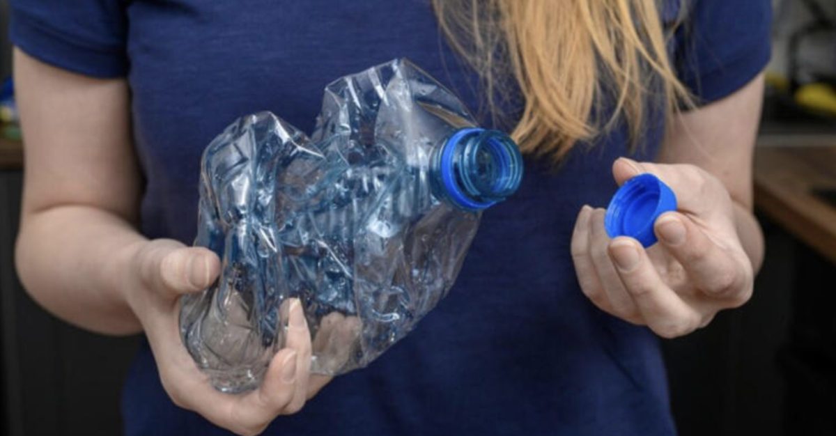 Personne tenant une bouteille en plastique PET écrasée avec son bouchon à la main, illustrant les consignes de tri sélectif et les bonnes pratiques pour le recyclage des bouteilles en plastique en France.