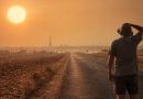 Homme se protégeant du soleil face à une route traversant un paysage desséché, avec la tour Eiffel au loin, illustrant le risque de canicule en France durant l’été 2027.