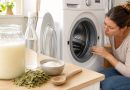 Femme examinant les dépôts dans son lave-linge à côté d’un bocal de lessive maison, de savon de Marseille et de bicarbonate de soude.