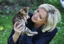 Marine Le Pen souriant et tenant dans ses mains un jeune chat bengal dans un jardin.