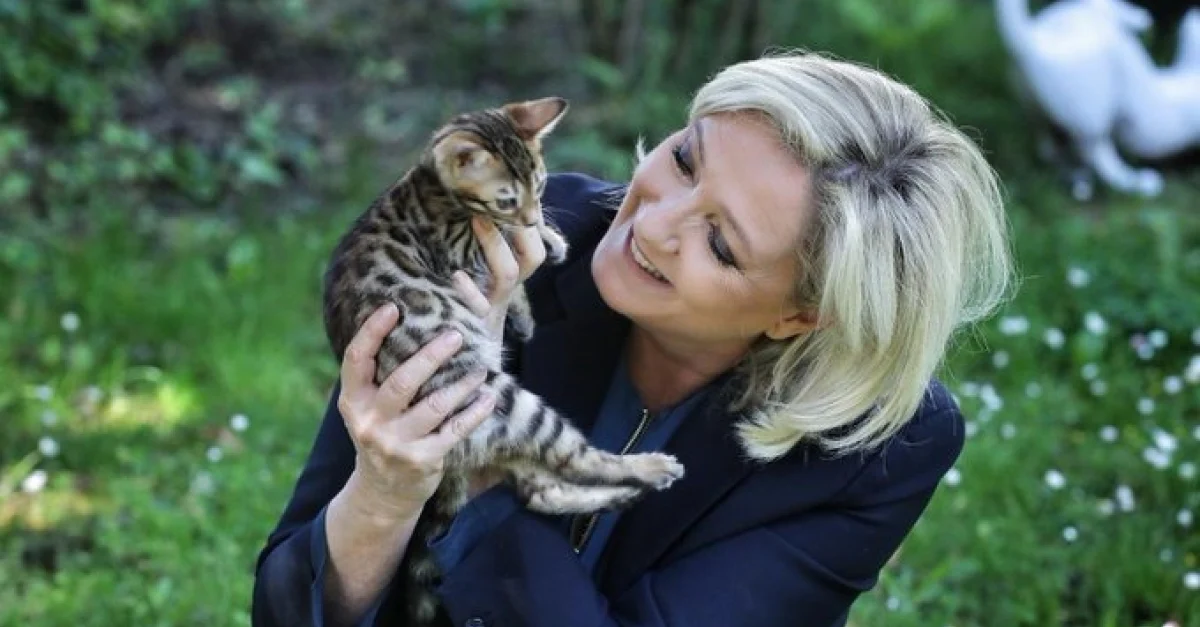 Marine Le Pen souriant et tenant dans ses mains un jeune chat bengal dans un jardin.