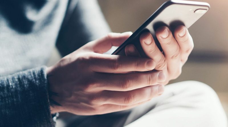 Une personne tient un smartphone entre ses mains et consulte un message reçu sur une application de messagerie. Cette image illustre un article sur la psychologie des messages laissés « en vu », les délais de réponse aux SMS et aux messages instantanés, les traits de personnalité pouvant influencer les habitudes de communication numérique, ainsi que les différentes raisons expliquant qu'une personne ne réponde pas immédiatement à un message.