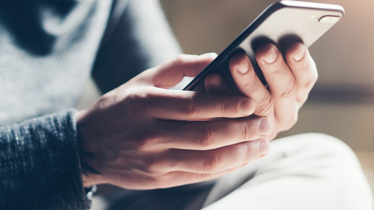 Une personne tient un smartphone entre ses mains et consulte un message reçu sur une application de messagerie. Cette image illustre un article sur la psychologie des messages laissés « en vu », les délais de réponse aux SMS et aux messages instantanés, les traits de personnalité pouvant influencer les habitudes de communication numérique, ainsi que les différentes raisons expliquant qu'une personne ne réponde pas immédiatement à un message.