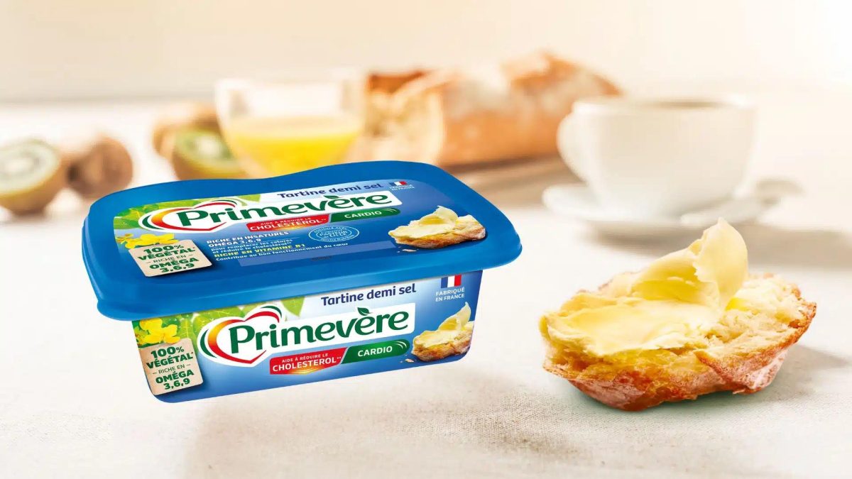 Barquette de Primevère Cardio Tartine Demi-Sel à côté d’une tranche de pain tartinée, matière grasse végétale riche en oméga-3, 6 et 9 présentée comme aidant à réduire le cholestérol.