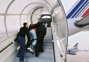 Un ressortissant algérien escorté par des agents des forces de l'ordre monte de force dans un avion dans le cadre d'une procédure d'expulsion liée à une OQTF après plusieurs refus d'embarquer vers l'Algérie.