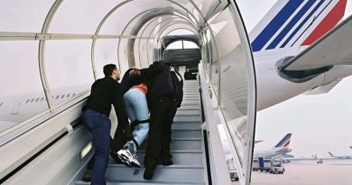 Un ressortissant algérien escorté par des agents des forces de l'ordre monte de force dans un avion dans le cadre d'une procédure d'expulsion liée à une OQTF après plusieurs refus d'embarquer vers l'Algérie.