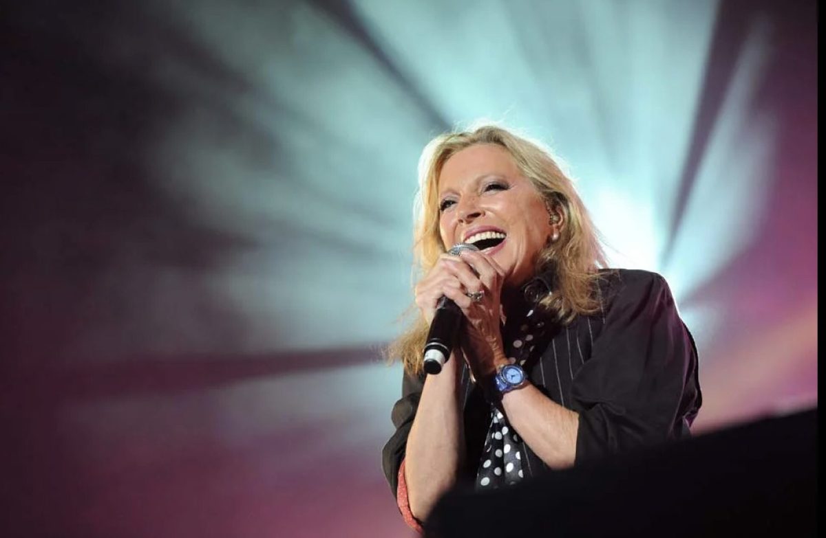 Véronique Sanson en concert, micro à la main, interprétant ses plus grands succès. Découvrez la biographie complète de la chanteuse française, sa carrière, ses chansons cultes et sa vie privée.
