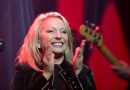 Véronique Sanson souriante sur scène lors d'un concert, applaudissant son public. La chanteuse française interprète ses plus grands succès au cours d'une carrière exceptionnelle débutée dans les années 1970.
