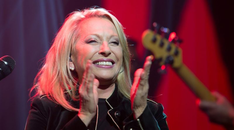 Véronique Sanson souriante sur scène lors d'un concert, applaudissant son public. La chanteuse française interprète ses plus grands succès au cours d'une carrière exceptionnelle débutée dans les années 1970.