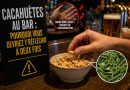 Bol de cacahuètes servi sur le comptoir d’un bar, dans lequel une personne plonge la main, avec une illustration de bactéries et de mains sales pour évoquer les risques de contamination liés aux cacahuètes partagées.