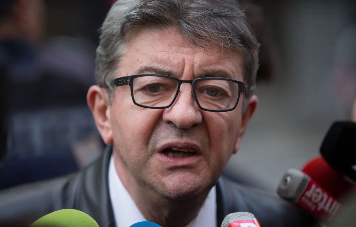 Jean-Luc Mélenchon portant des lunettes et s’exprimant devant plusieurs micros, illustration de l’article sur l’ancienne vidéo « Pourquoi tu te déguises en Afghan ? » qui refait surface en 2026.