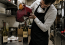 Serveur dans l’arrière-cuisine d’un restaurant remplissant une bouteille de vin à l’aide d’un cubi, illustration du rempotage et de la substitution frauduleuse de vin au restaurant.