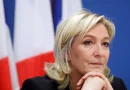 Portrait d’une femme politique française devant un drapeau tricolore, illustration du projet du RN visant à interdire le voile dans l’espace public et à sanctionner son port par une amende en cas de victoire à la présidentielle de 2027.