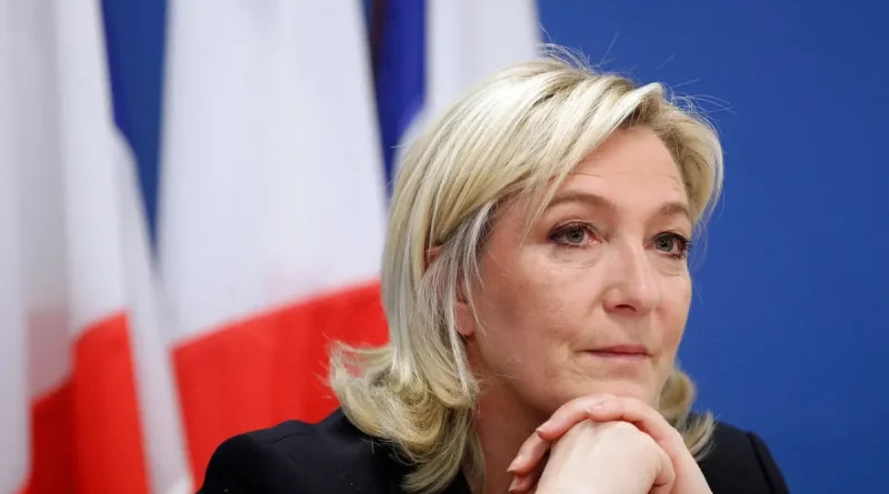 Portrait d’une femme politique française devant un drapeau tricolore, illustration du projet du RN visant à interdire le voile dans l’espace public et à sanctionner son port par une amende en cas de victoire à la présidentielle de 2027.