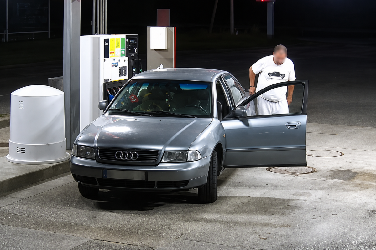 Capture de vidéosurveillance montrant une Audi grise stationnée devant une pompe à essence d'une station-service Super U à Revel-Tourdan, en Isère. Un homme au visage volontairement flouté se tient à côté de la portière ouverte de son véhicule. Cette image illustre le fait divers dans lequel le magasin a diffusé une capture de vidéosurveillance afin de dénoncer une incivilité commise sur son site.