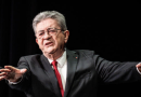 Responsable politique français en costume sombre et cravate rouge prenant la parole sur scène, illustration de la plainte visant Jean-Luc Mélenchon pour ses propos « tout blancs, tout moches »
