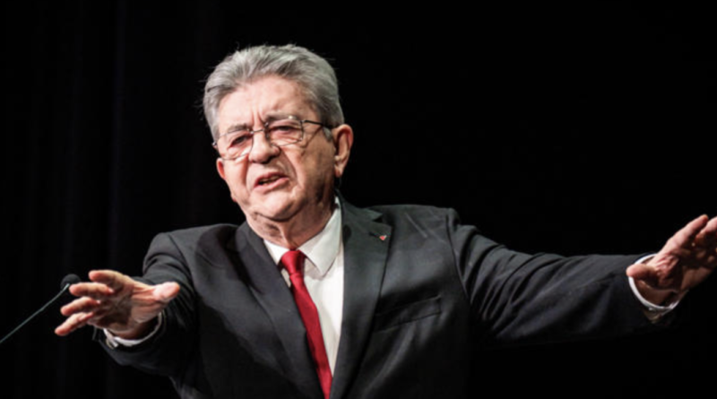 Responsable politique français en costume sombre et cravate rouge prenant la parole sur scène, illustration de la plainte visant Jean-Luc Mélenchon pour ses propos « tout blancs, tout moches »