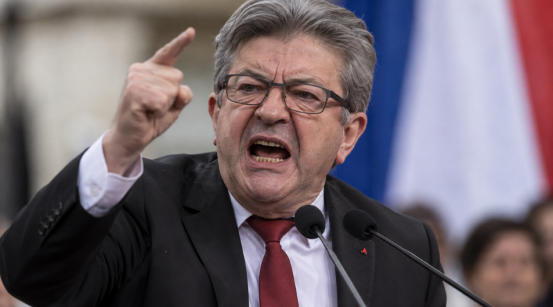 Jean-Luc Mélenchon, fondateur de La France insoumise (LFI), photographié dans une attitude très véhémente lors d’une prise de parole politique, le visage tendu, la bouche ouverte et l’index levé devant des micros, avec les couleurs du drapeau français en arrière-plan.