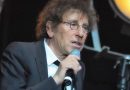 Alain Souchon, portant des lunettes et un costume sombre, s'exprime dans un micro sur scène. Le chanteur français a suscité une polémique en évoquant un départ en Suisse en cas de victoire du Rassemblement national, avant d'être défendu par Pierre Arditi. Copier l'ALT