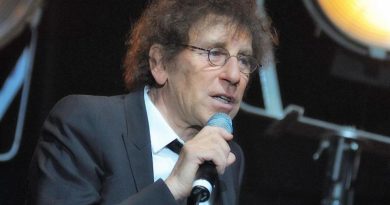 Alain Souchon, portant des lunettes et un costume sombre, s'exprime dans un micro sur scène. Le chanteur français a suscité une polémique en évoquant un départ en Suisse en cas de victoire du Rassemblement national, avant d'être défendu par Pierre Arditi. Copier l'ALT