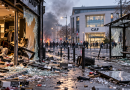 Illustration générée par intelligence artificielle représentant une rue française après des dégradations urbaines, avec une vitrine de magasin brisée, un abribus vandalisé, des débris sur la chaussée et un bâtiment de la CAF en arrière-plan. L'image illustre le projet du gouvernement visant à renforcer la responsabilité financière des casseurs et des pilleurs, notamment par des mesures concernant certaines prestations sociales.