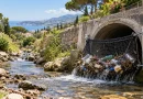 Filet anti-déchets installé à la sortie d'une canalisation d'eaux pluviales, retenant bouteilles en plastique, canettes et emballages pour illustrer la lutte contre la pollution marine à Cannes.